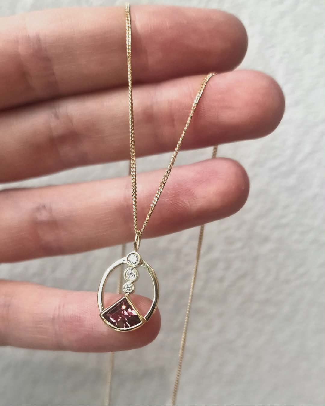 Gouden hanger met edelsteen uit de eigen collectie van Komorebi, vastgehouden in een hand
