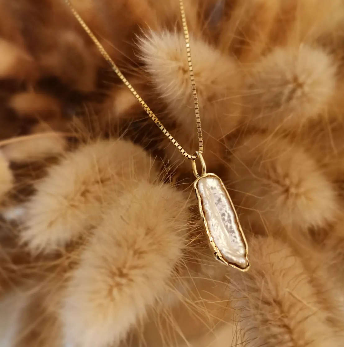 Hanger in 18kt geelgoud met een langwerpige parel tussen droogbloemen