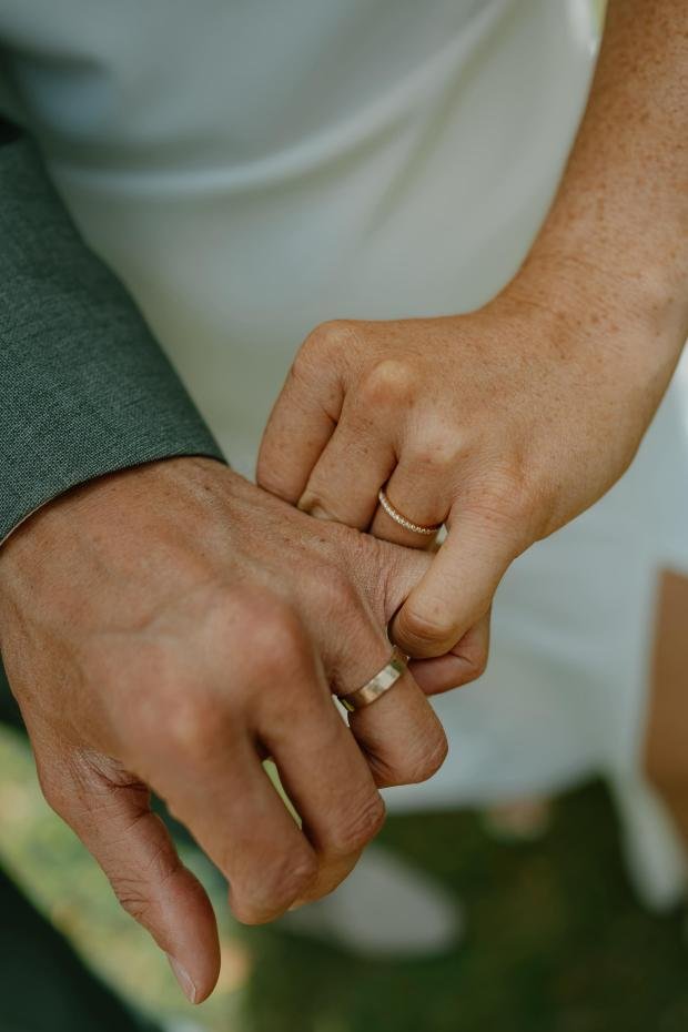 Bruidspaar hand in hand met gouden trouwringen