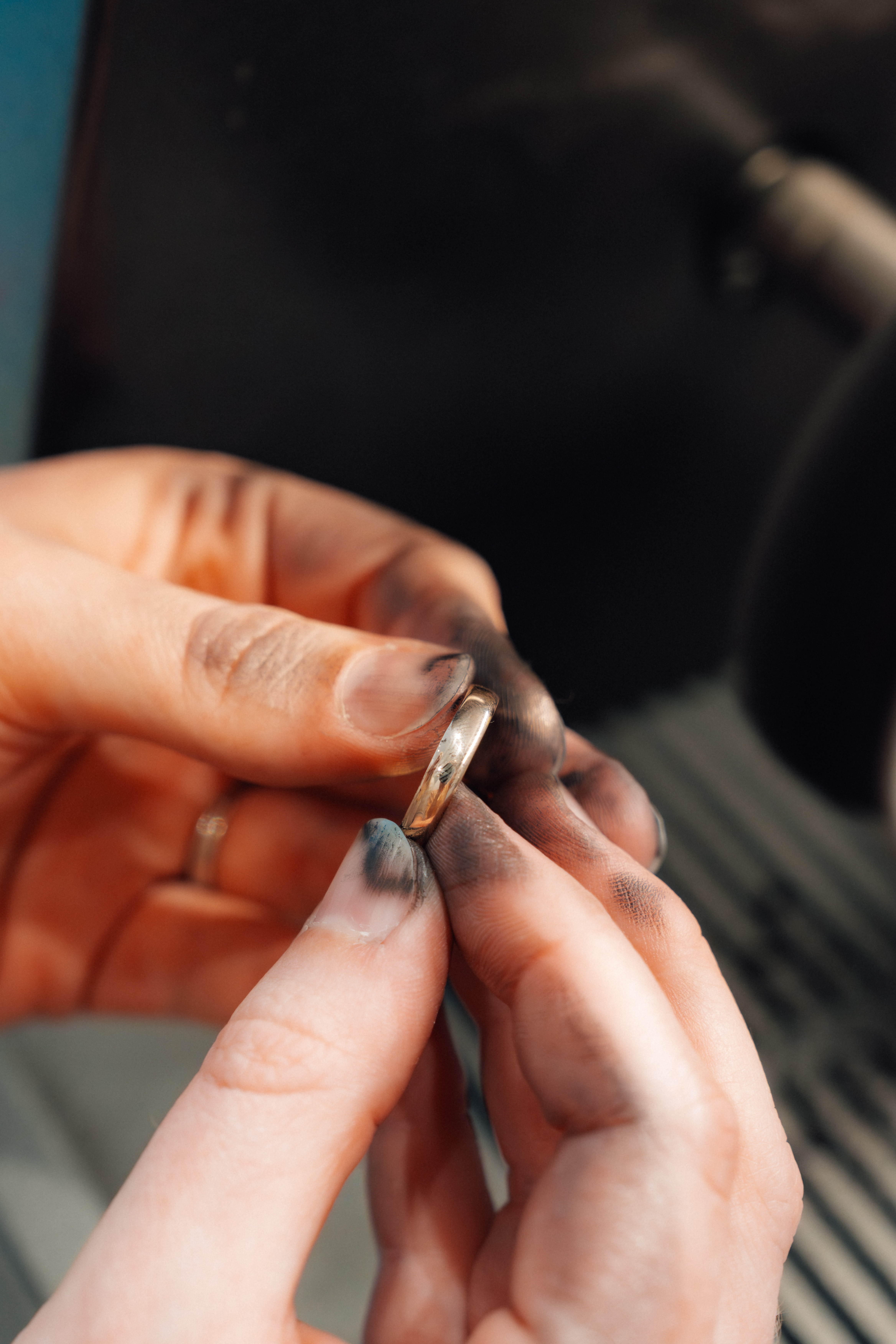 Handen van de goudsmid die een ring opschuren tijdens een herstelling