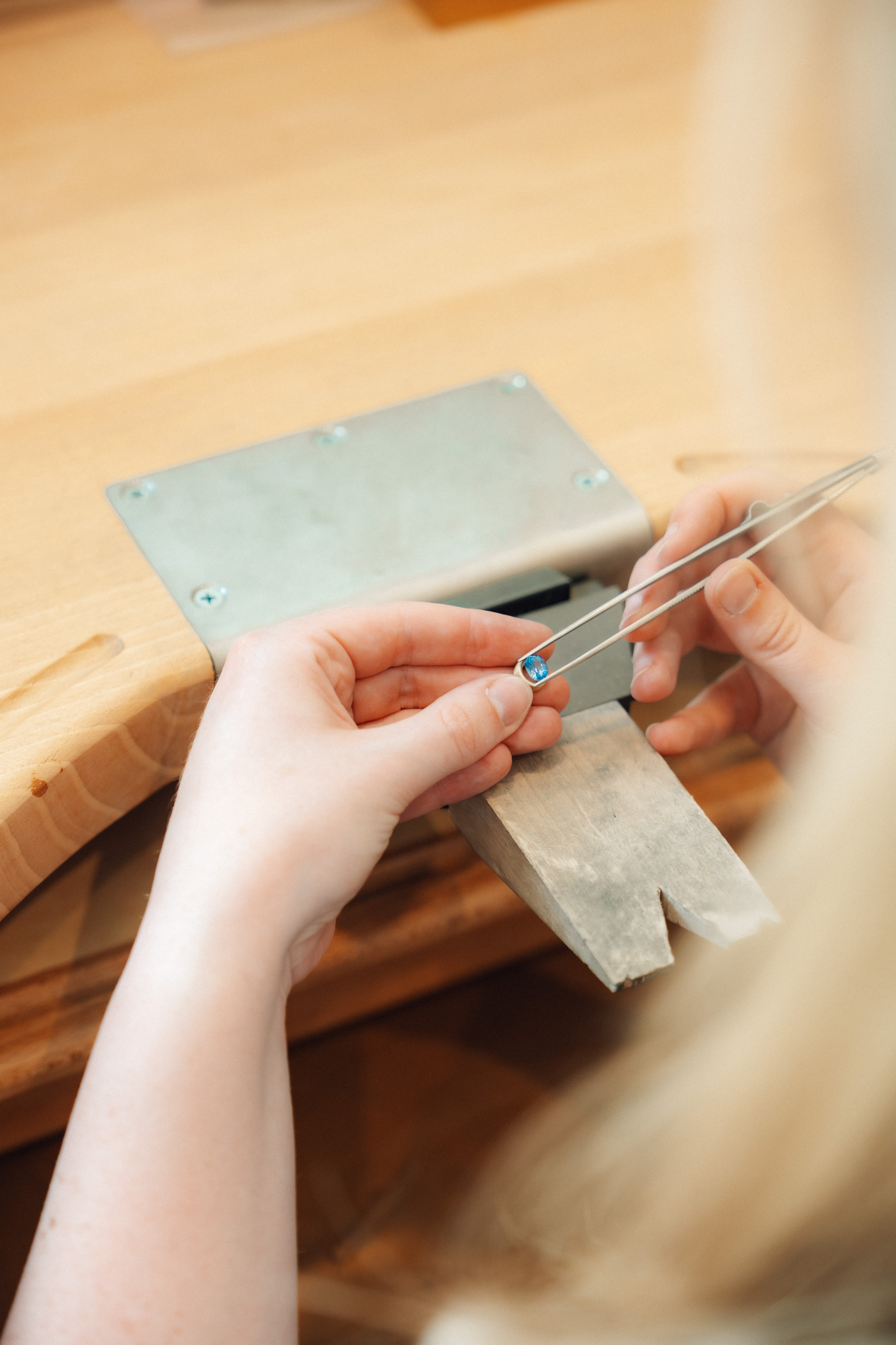 De goudsmid zaagt een stuk metaal aan de werkbank in het atelier