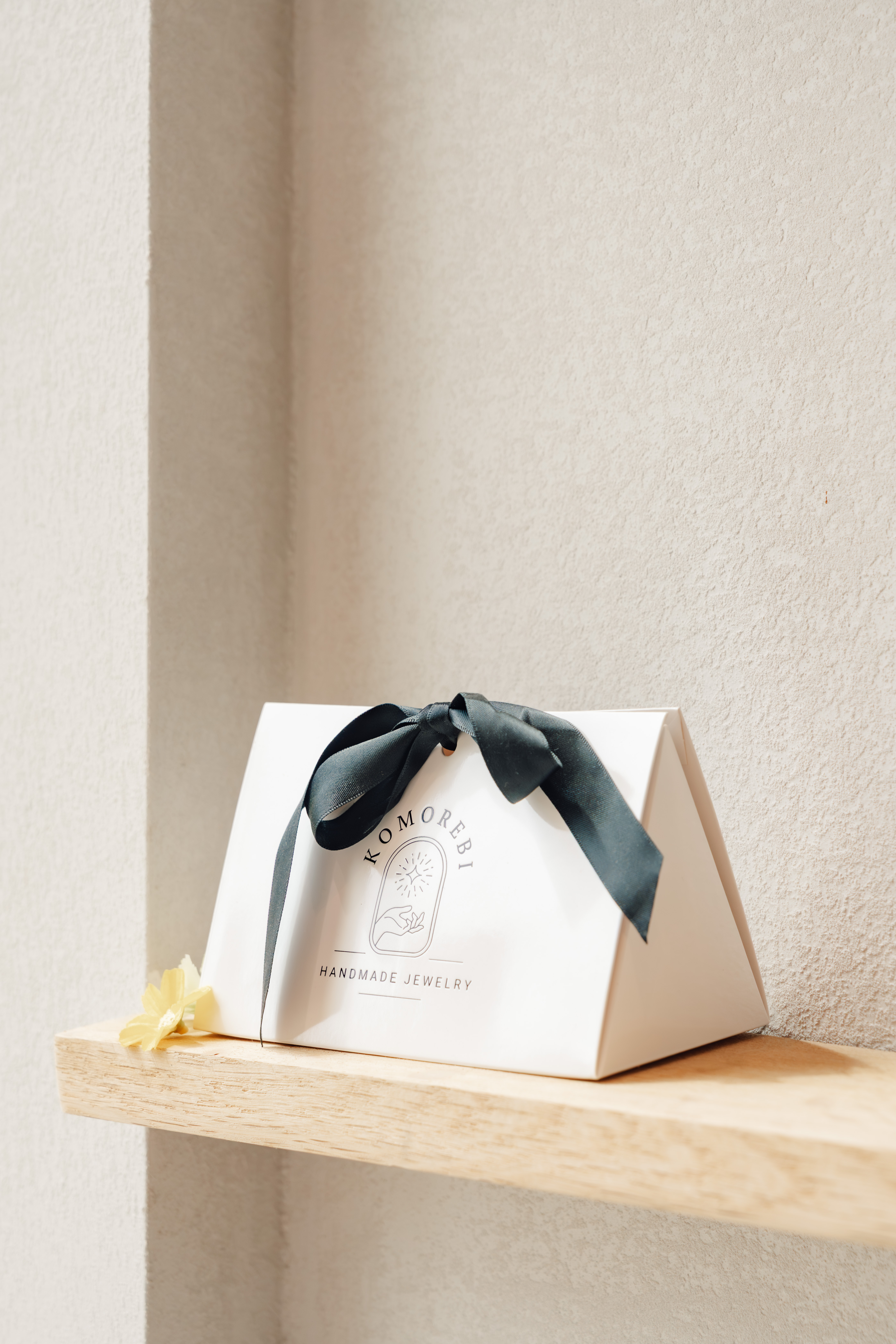 Geschenkverpakking van Komorebi met donkergroen lint op een houten plankje